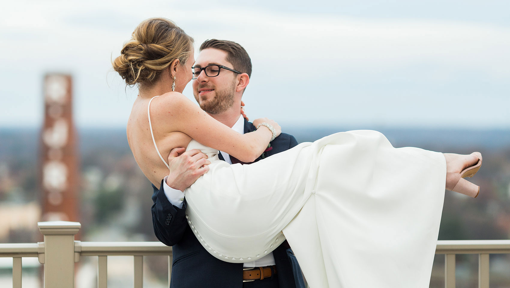 Bride in groom’s arms with Winston Salem in background